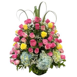 Jardín floral con 100 rosas fucsia y amarillas, hortensias azules y follaje.